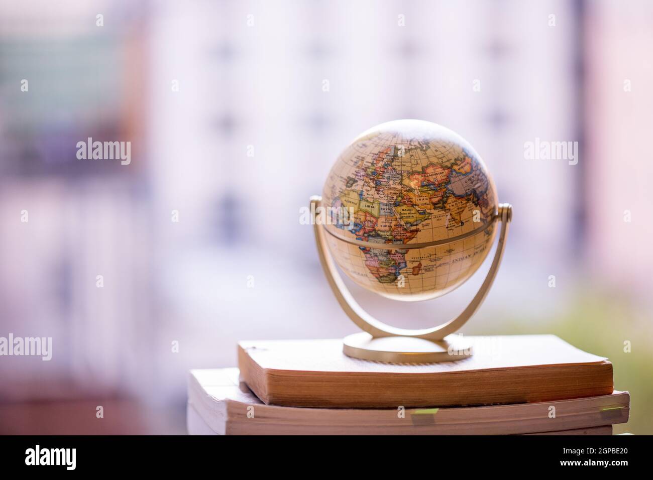 Miniatura modello globo in piedi su una pila di libri. Simbolo per il viaggio. Foto Stock