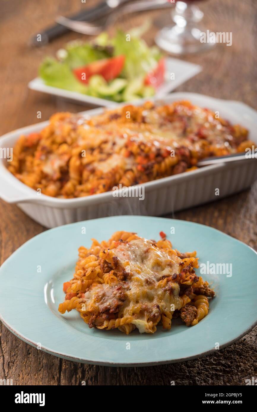 pasta gratinata con insalata su legno Foto Stock