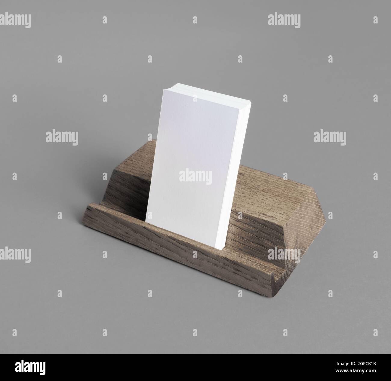 Porta carte di credito in legno con biglietti da visita vuoti su sfondo grigio. Foto Stock