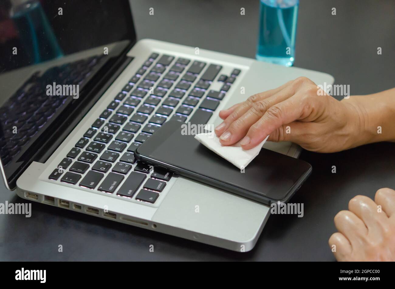 Pulire e disinfettare il telefono cellulare con alcol. Concetto di assistenza sanitaria Foto Stock