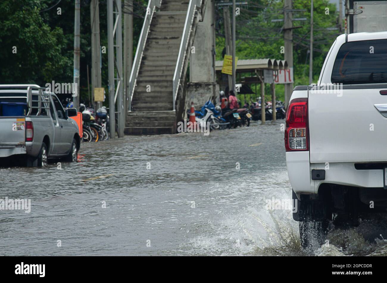 La pioggia battente allaga le strade della Thailandia. L'auto passa attraverso l'acqua allagata. Foto Stock