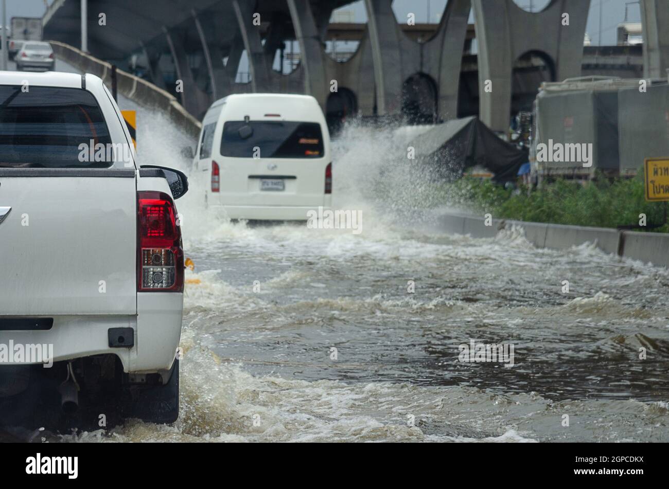 La pioggia battente allaga le strade della Thailandia. L'auto passa attraverso l'acqua allagata. Foto Stock