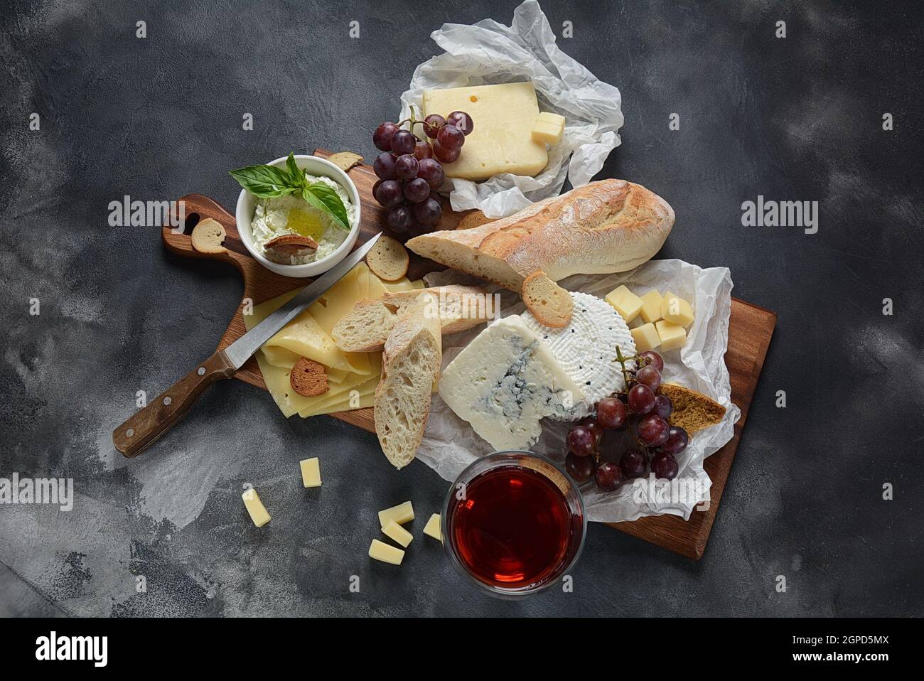 Piatto di formaggi con formaggi assortiti, uva, spuntini su sfondo scuro. Antipasto italiano e francese Foto Stock