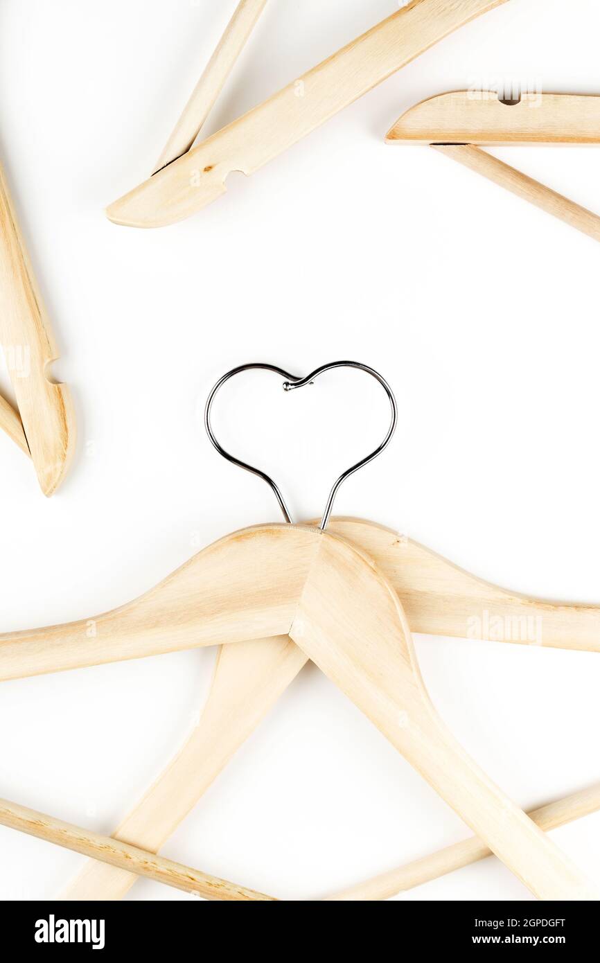 Consumo consapevole concetto di moda lenta. Cuore di appendiabiti intrecciati su sfondo bianco. Foto Stock