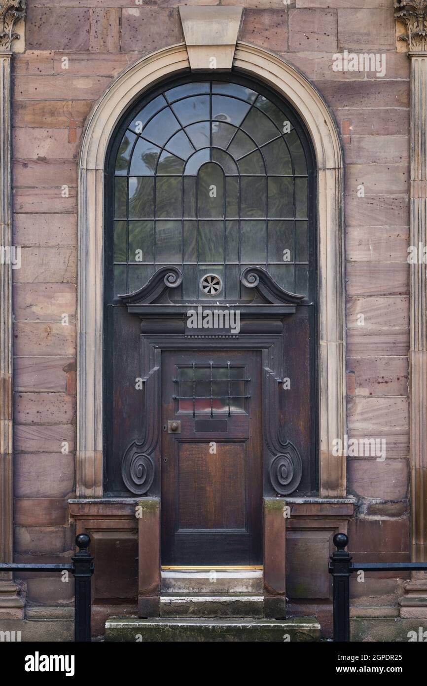Antica porta in legno massiccio sul lato della storica chiesa in pietra. Solida architettura esterna della porta chiusa in barre ad arco su finestre ad alta sicurezza. Foto Stock