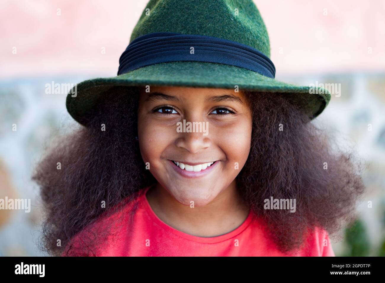 Bella ragazza con lunghi capelli afro in giardino con un elegante cappello  nero Foto stock - Alamy