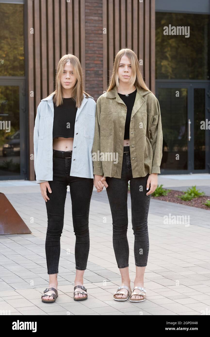 Due ragazze gemelle bionde in casualwear che si oppone all'architettura moderna in strada Foto Stock