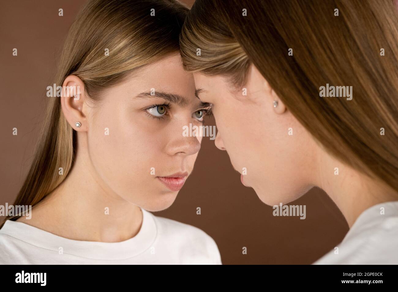 Una delle due ragazze teenage bionda che guardano la sua sorella gemella davanti alla macchina fotografica Foto Stock