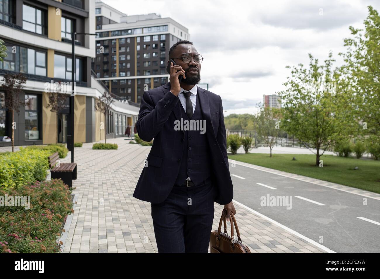 Banchiere occupato di etnia africana che parla al telefono cellulare in ambiente urbano Foto Stock
