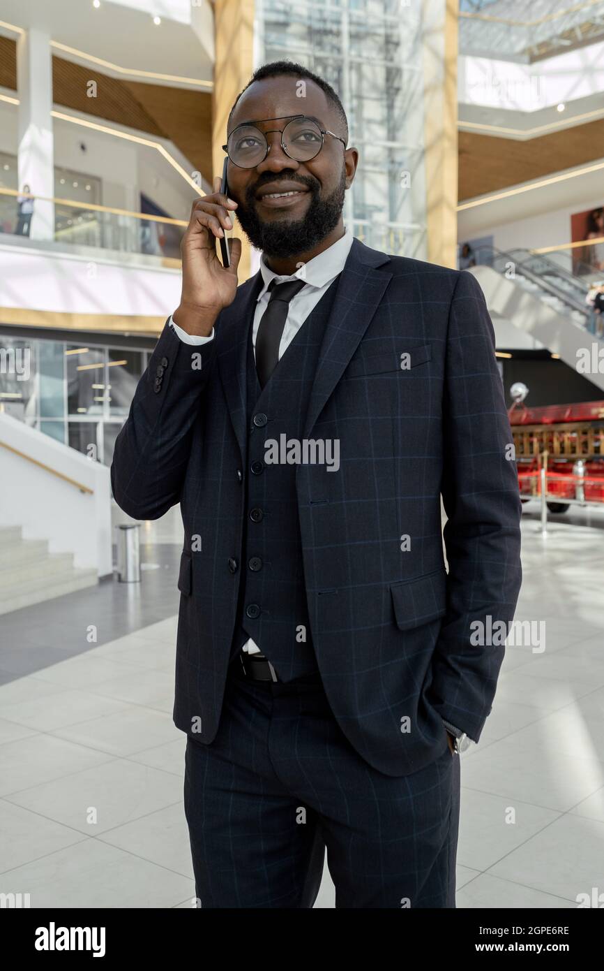 Giovane uomo ben vestito di etnia africana che parla sul cellulare di fronte alla macchina fotografica Foto Stock