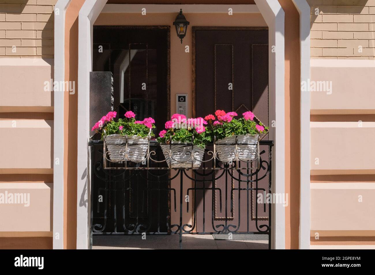 Design paesaggistico in città. Vasi di fiori e piante in fiore si trovano vicino alla finestra all'ingresso della casa. Concetto di design residenziale. Foto Stock