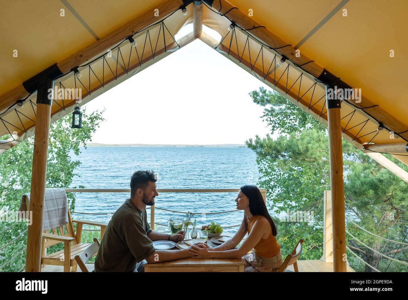 Giovane coppia romantica cena al mare durante il riposo in tenda glamping Foto Stock