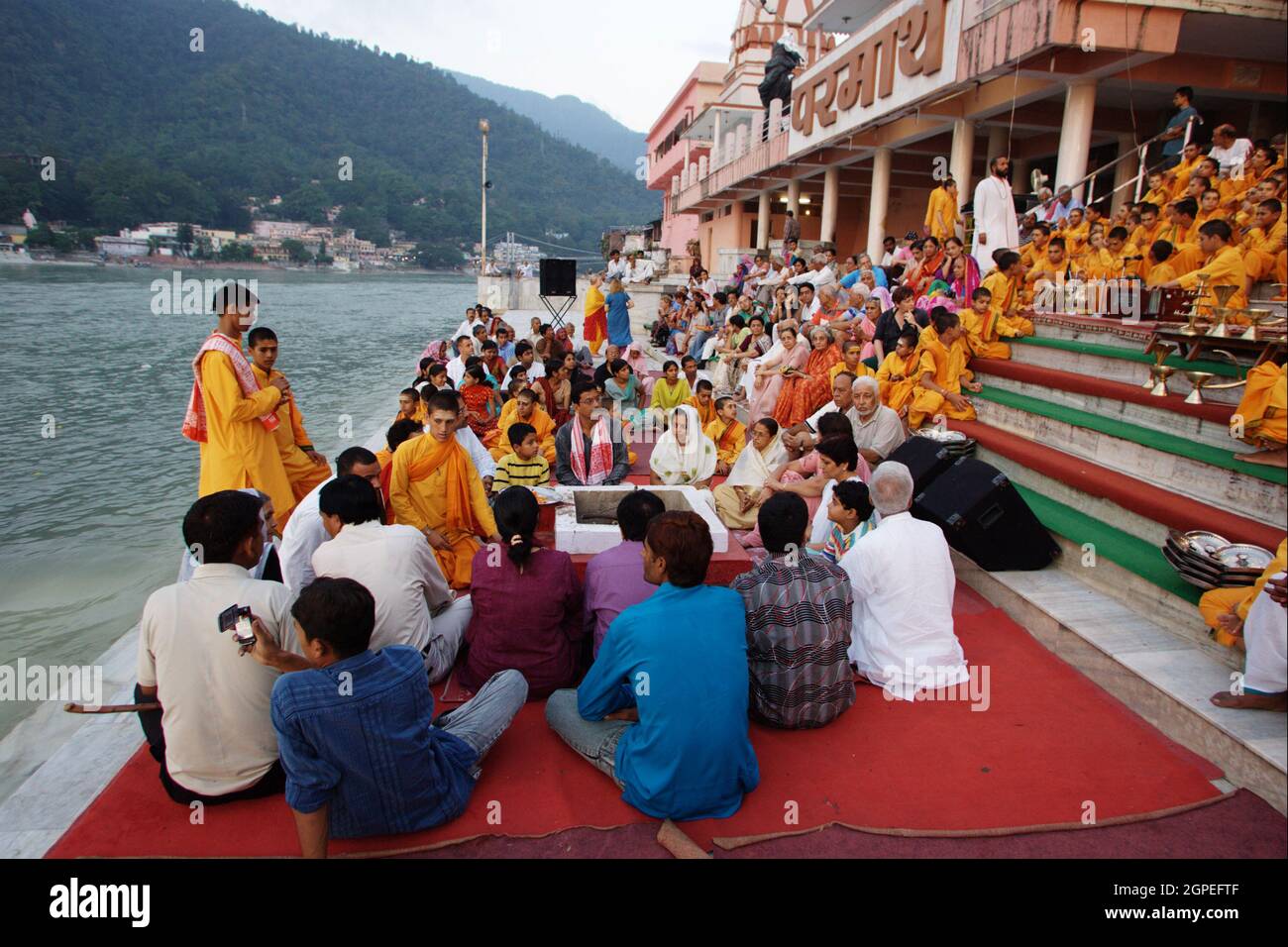 Spettatori, credenti, seguaci e sacerdoti in abiti arancioni nella città Santa di Rishikesh a Uttarakhand, in India durante la cerimonia leggera della sera cal Foto Stock