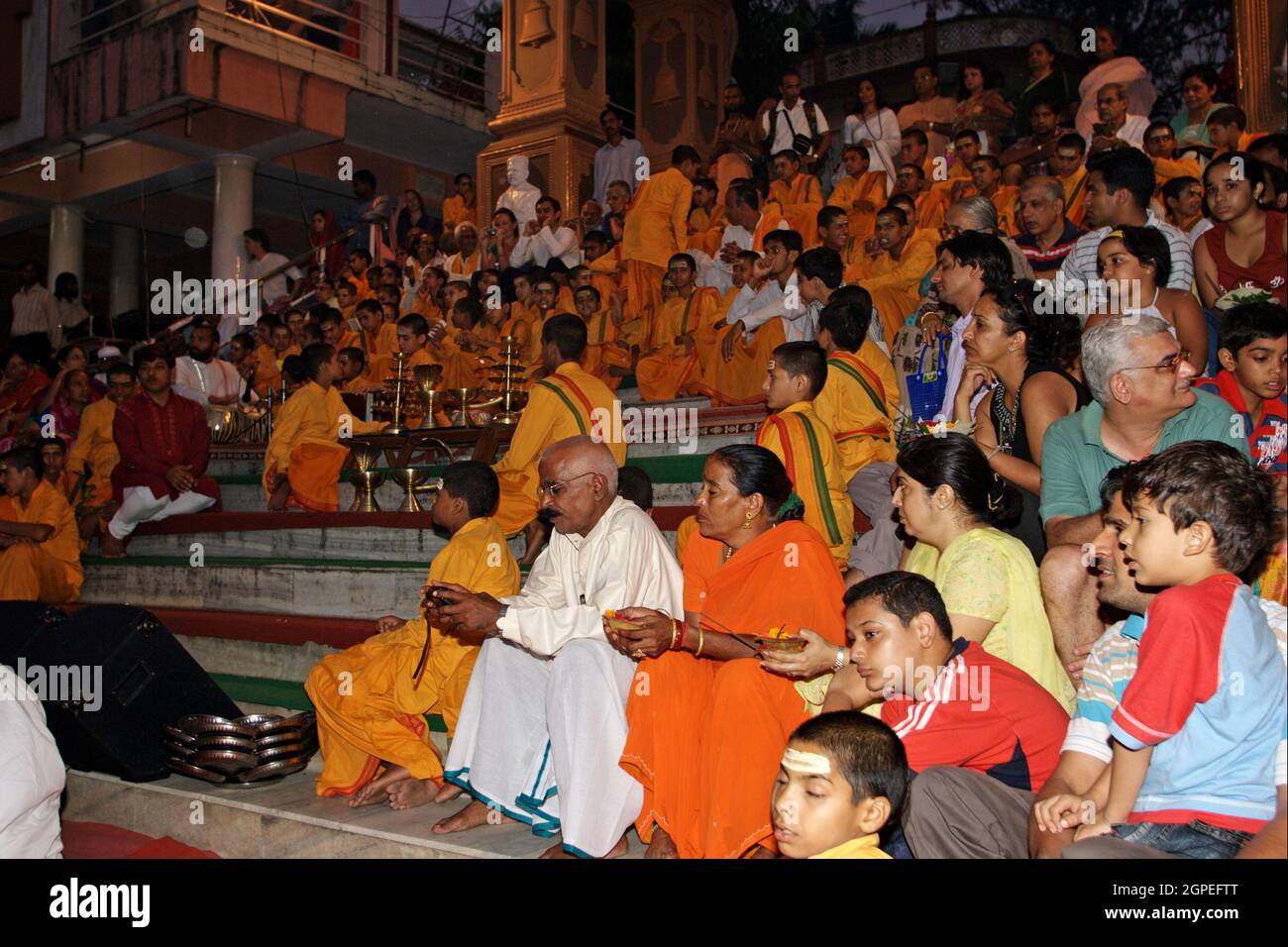 Spettatori, credenti, seguaci e sacerdoti in abiti arancioni nella città Santa di Rishikesh a Uttarakhand, in India durante la cerimonia leggera della sera cal Foto Stock