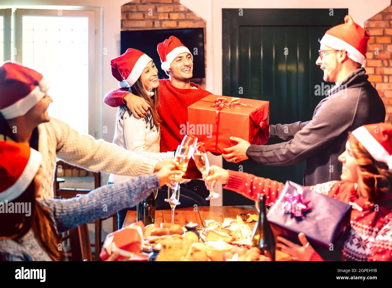 Amici con santa Hat che si danno reciprocamente regalo di Natale - Champagne vino brindisi a casa x mas cena partito - concetto di vacanza con la gente che si diverte Foto Stock
