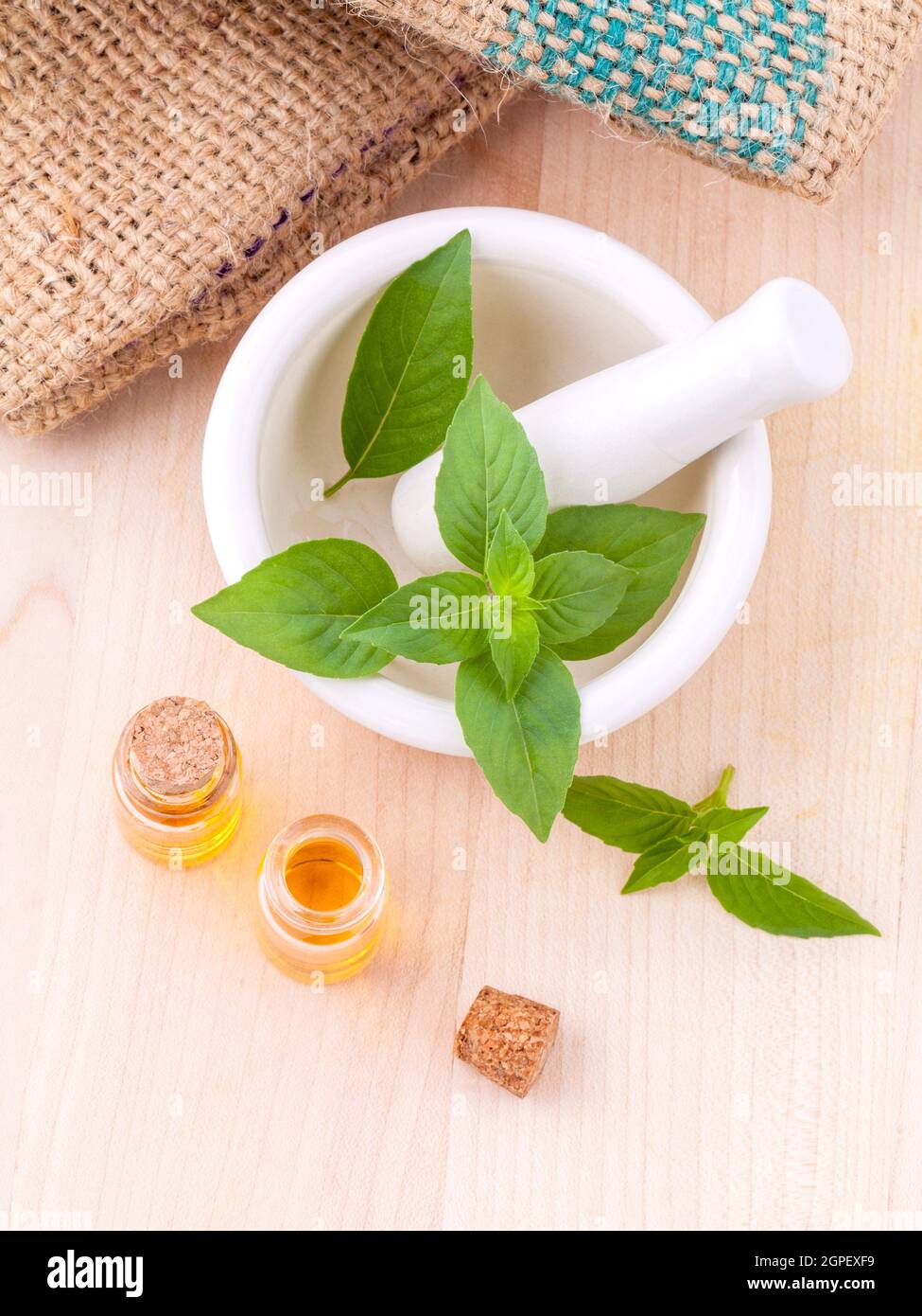 Medicina alternativa basilico limone olio naturale terme ingredienti per aroma aromaterapia con mortaio su sfondo di legno. Foto Stock