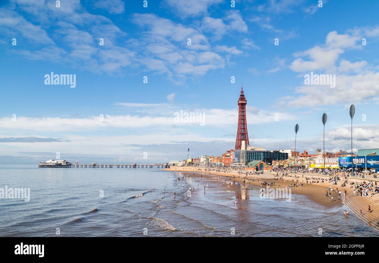 I turisti entrano in acqua quando la marea inizia a uscire sulla spiaggia di Blackpool nel settembre 2021. Il North Pier e la Blackpool Tower occupano lo sfondo Foto Stock