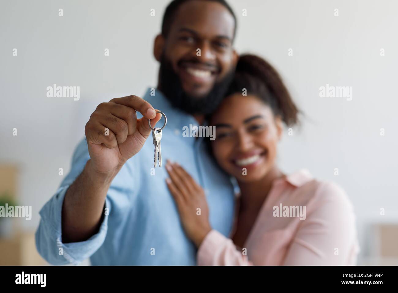 Sorridente giovane afro americano coppia abbracciando e mostrare le chiavi di nuovo albergo a casa interno Foto Stock