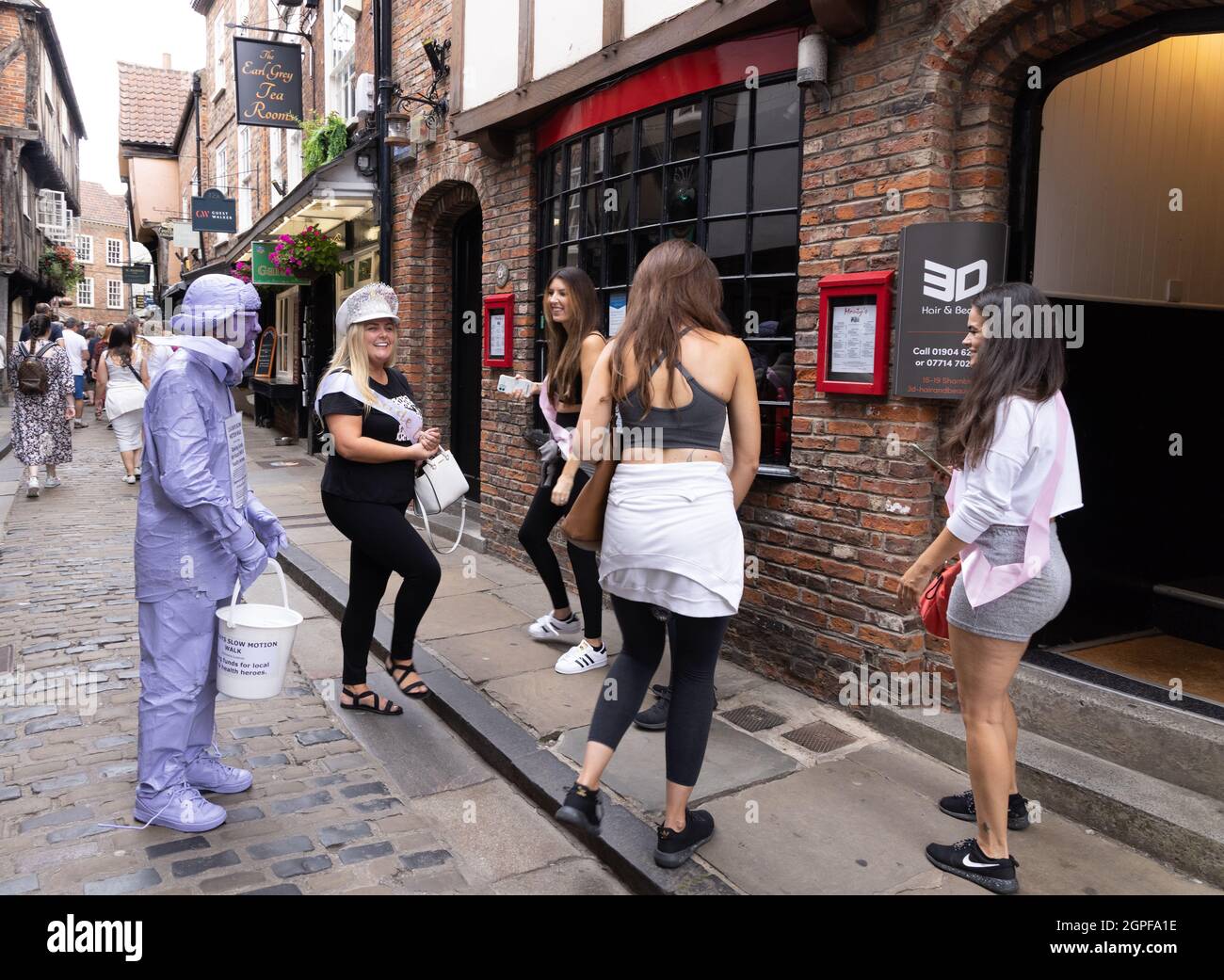 Street Photography; Hen party UK; donne in un partito di galline con un operaio di beneficenza in costume, The Shambles, York City Center, Yorkshire UK Foto Stock