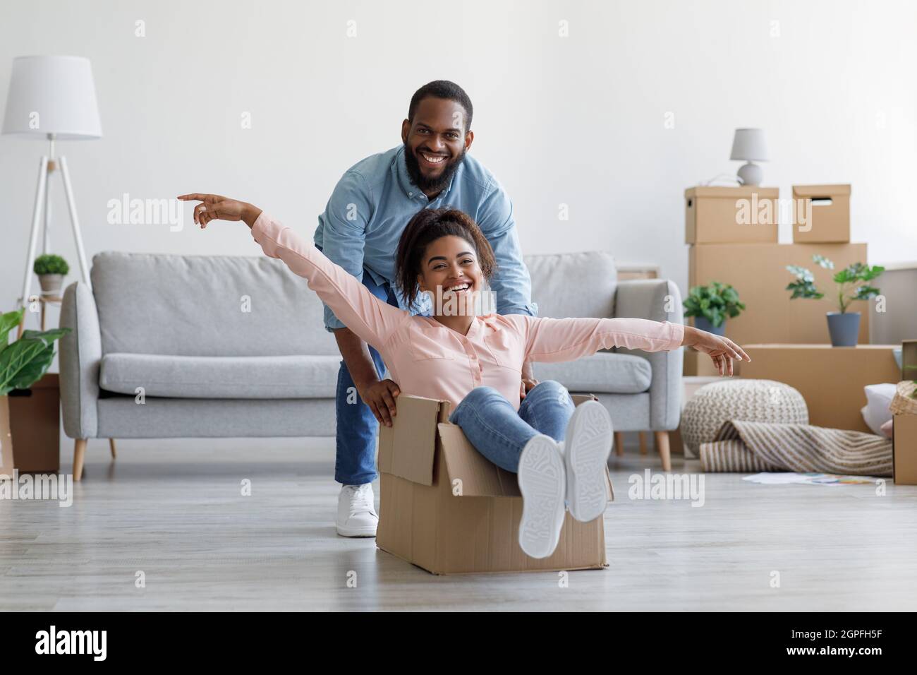 Felice nero millennial coppia in casa propria, i compratori hanno divertimento, ridendo sul giorno commovente Foto Stock