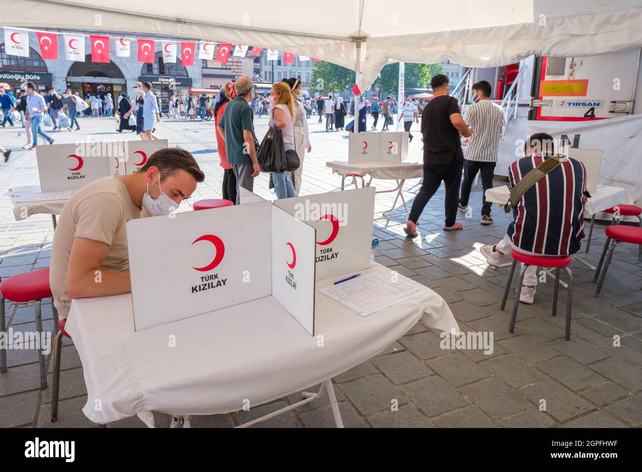Eminonu, Istanbul, Turchia - 07.05.2021: Diversi volontari per le donazioni di sangue firmi una lista di controllo per l'approvazione ufficiale su un tavolo sotto una tenda di rosso turco Foto Stock