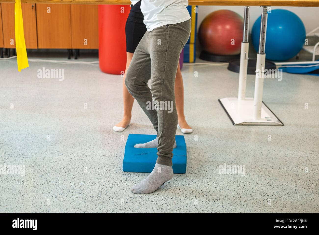 Pazienti maschi gambe facendo esercizi di bilanciamento pad con l'aiuto di una terapeuta femminile. Foto Stock