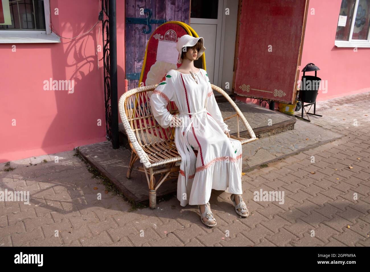 Un manichino femminile in un abito bianco di lino chiaro si siede su una  panca all'ingresso della strada Foto stock - Alamy