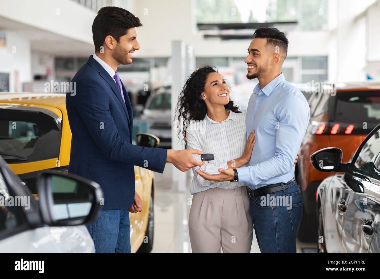 Sorridente responsabile delle vendite che dà la chiave di famiglia medio-orientale da auto Foto Stock