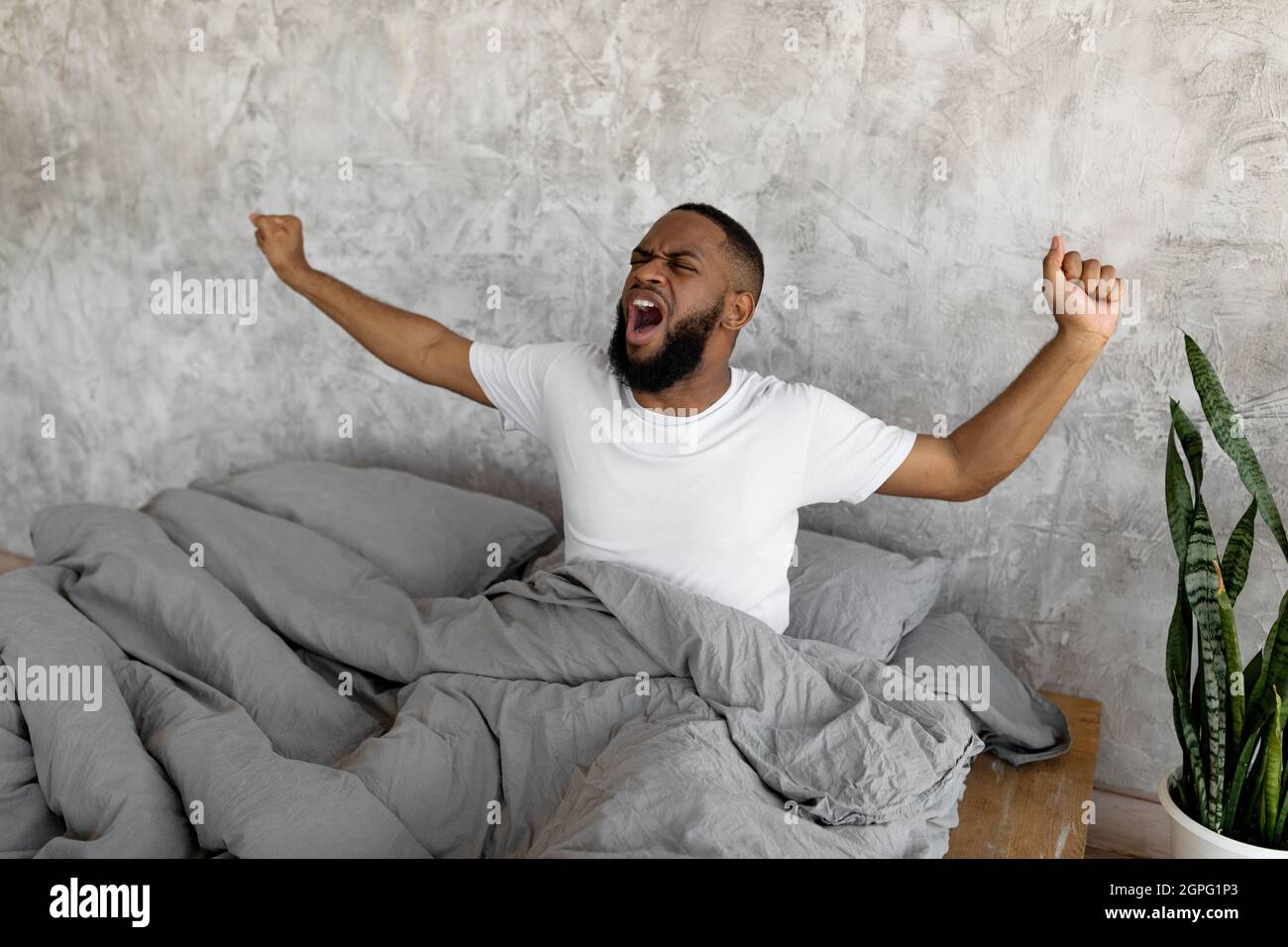 Sonnolento giovane afroamericano sbadigliante che si allunga dopo il risveglio Foto Stock