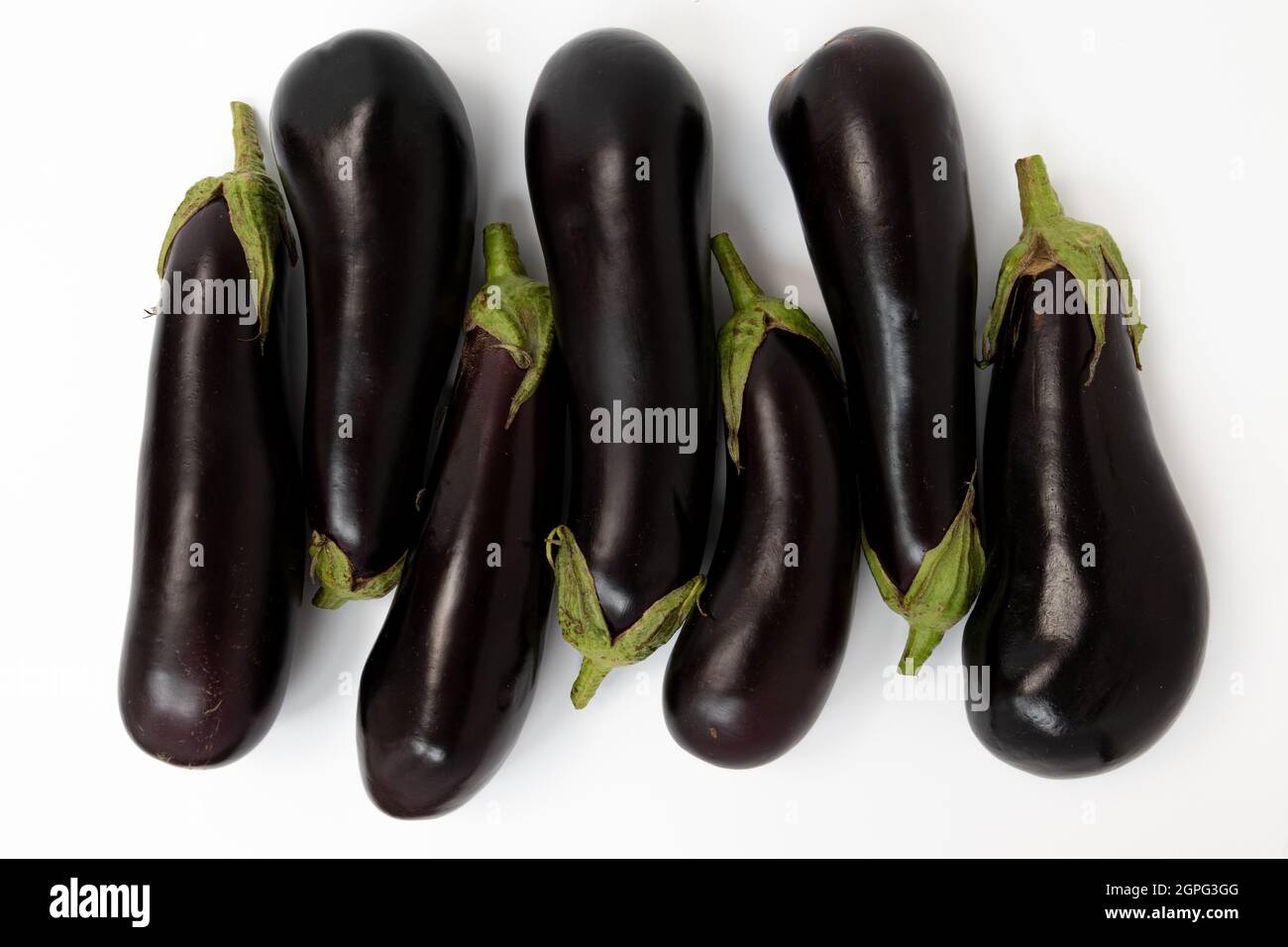 melanzane fresche isolate su sfondo bianco, primo piano di sette melanzane intere, vista dall'alto Foto Stock