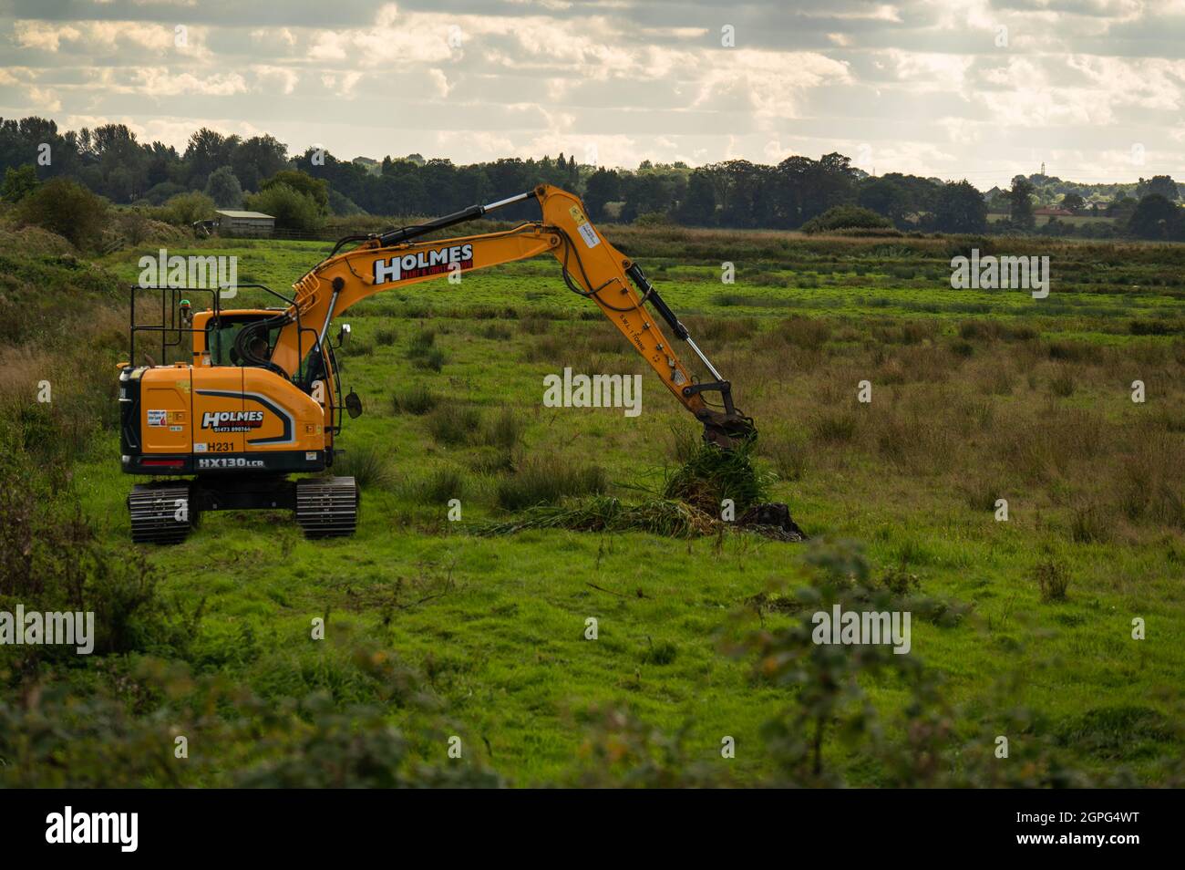 Un scavatore che mantiene fossi drenanti su paludi di pascolo basse-menzogne sui Broads di Norfolk alle paludi di Buckenham Foto Stock