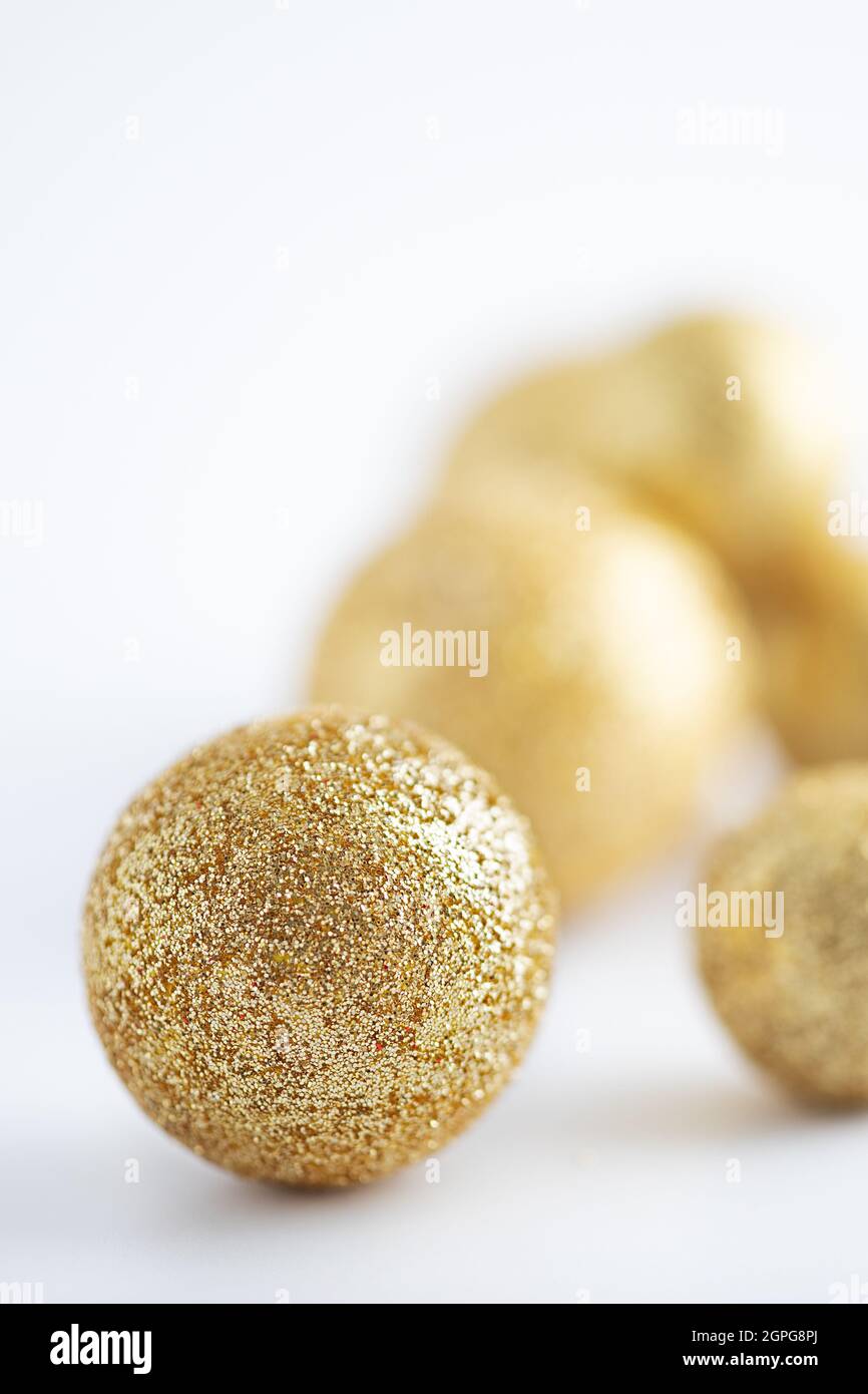 palle di natale ricoperte di glitter dorata su sfondo bianco Foto Stock