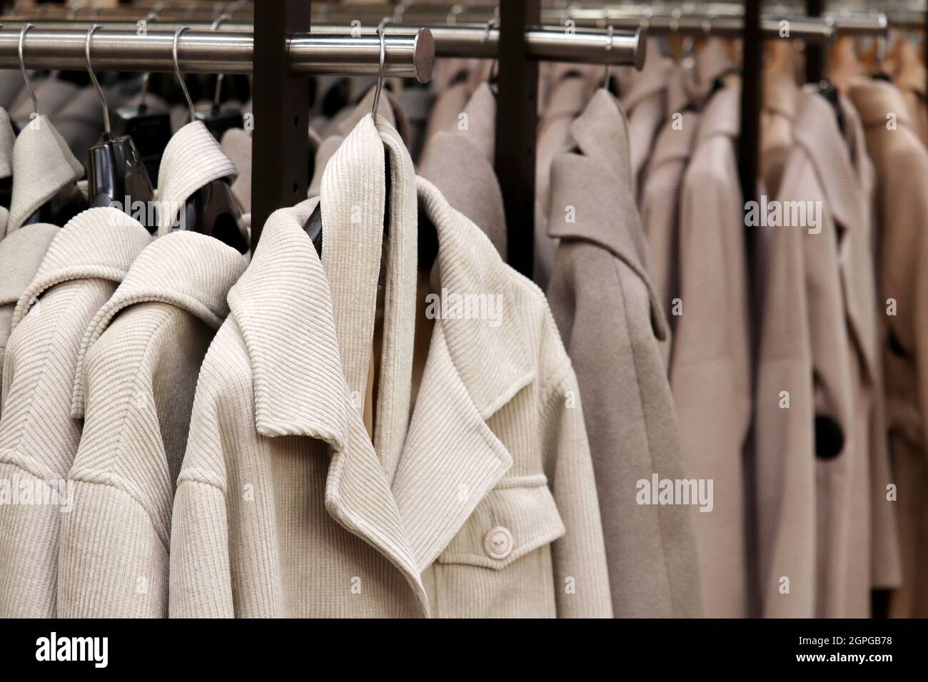 Cappotti femminili in fila su un appendiabiti nel negozio. Nuova collezione moda autunnale Foto Stock
