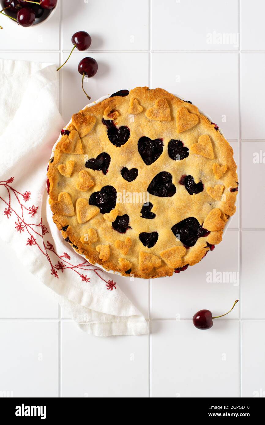 Torta di ciliegia aperta fatta in casa con reticolo su sfondo grigio di cemento. Messa a fuoco selettiva. Vista dall'alto Foto Stock