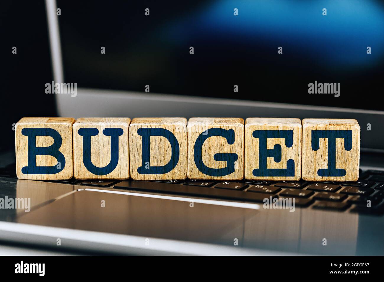 tema di bilancio. cubi di legno con la parola budget, sullo sfondo del portatile Foto Stock