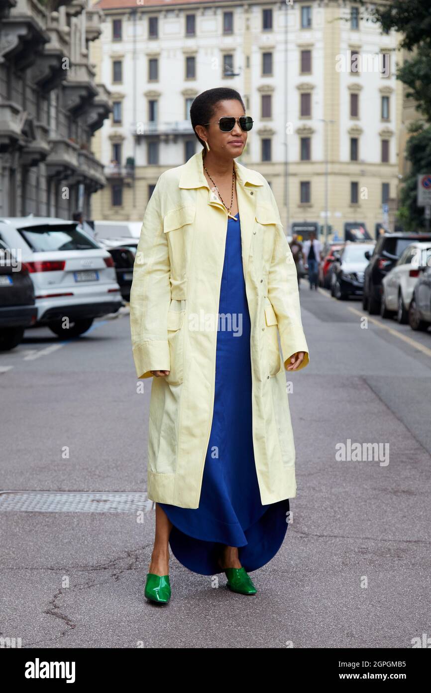 MILANO, ITALIA - 25 SETTEMBRE 2021: Tamu McPherson con giallo pallido, cappotto lungo, abito blu elettrico e scarpe a punta verde davanti a Salvatore Ferragamo Foto Stock