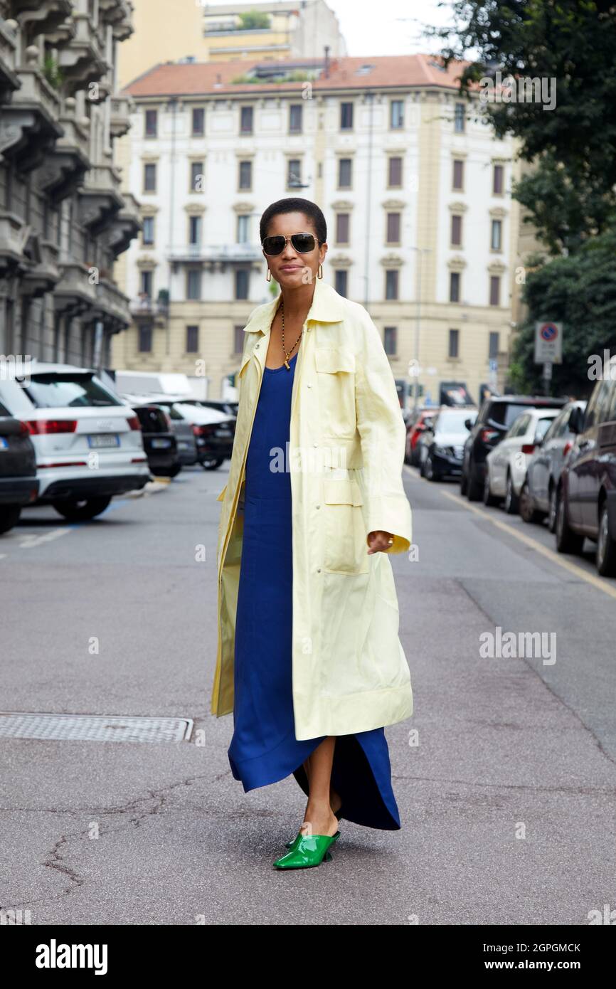 MILANO, ITALIA - 25 SETTEMBRE 2021: Tamu McPherson con giallo pallido, cappotto lungo, abito blu elettrico e scarpe a punta verde davanti a Salvatore Ferragamo Foto Stock