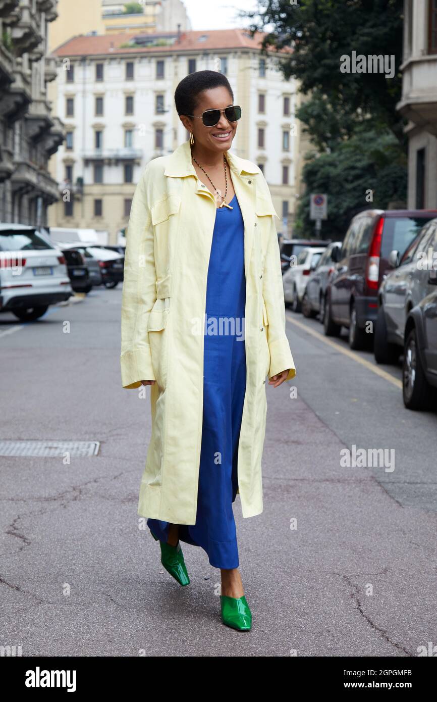 MILANO, ITALIA - 25 SETTEMBRE 2021: Tamu McPherson con giallo pallido, cappotto lungo, abito blu elettrico e scarpe a punta verde davanti a Salvatore Ferragamo Foto Stock
