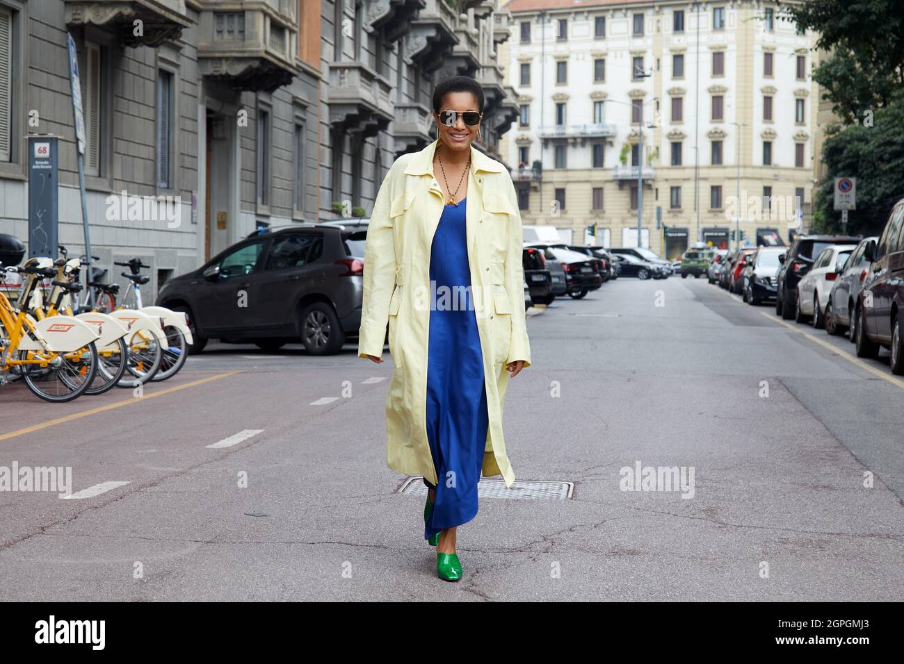 MILANO, ITALIA - 25 SETTEMBRE 2021: Tamu McPherson con giallo pallido, cappotto lungo, abito blu elettrico e scarpe a punta verde davanti a Salvatore Ferragamo Foto Stock