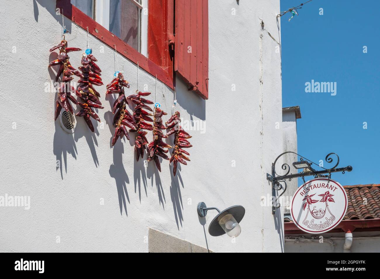 Francia, Pirenei Atlantici, Pays Basque, Espelette, chilis che asciuga al sole di fronte a una casa tradizionale Foto Stock