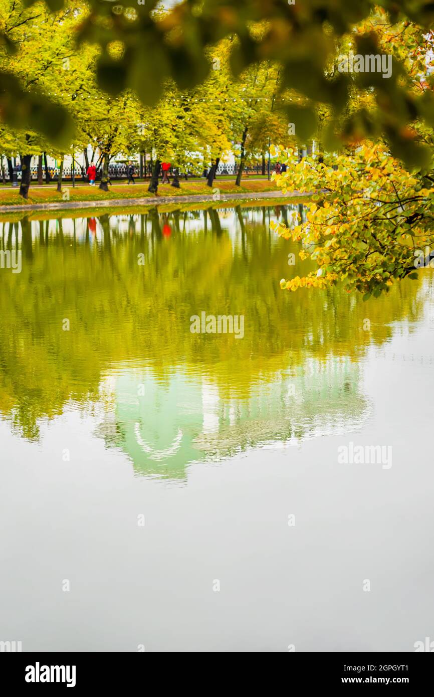 Giornata autunnale soleggiata in città. Bella vista panoramica di boulevard e stagno, l'edificio e gli alberi si riflettono in acqua Foto Stock