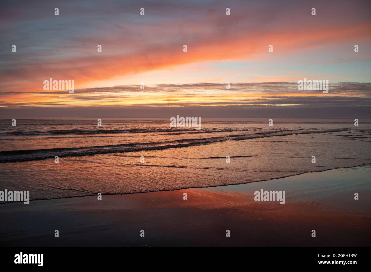 Tramonto sulla spiaggia con le onde Foto Stock