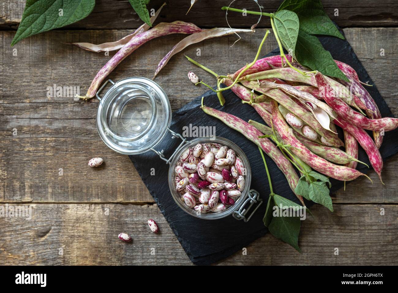 Fagioli di fagiolo, fagiolo marrone (di fagiolini secchi) in un vaso di vetro su un tavolo rustico. Sfondo alimentare. Vista dall'alto sfondo piatto. Spazio di copia. Foto Stock