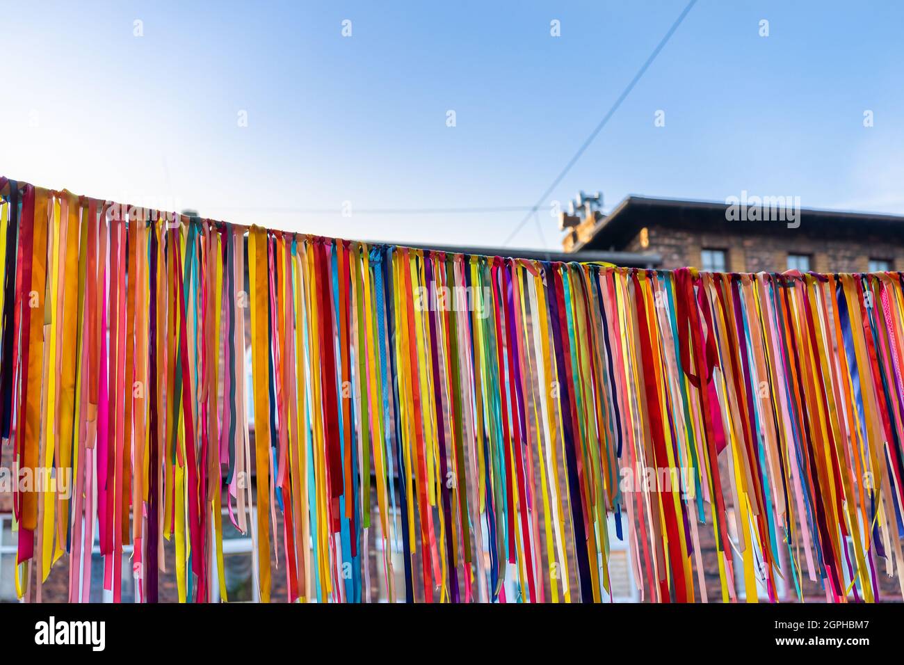 Garland fatto di nastri colorati appesi fuori l'edificio nel quartiere storico Nikiszowiec a Katowice, Slesia, Polonia. Cielo blu nel backgro Foto Stock