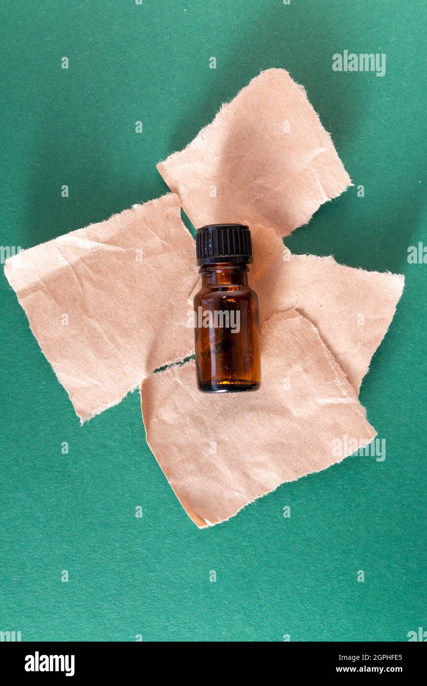 Bottiglia in vetro con olio aromatico e carta strappata, prodotti per la cura della pelle Foto Stock