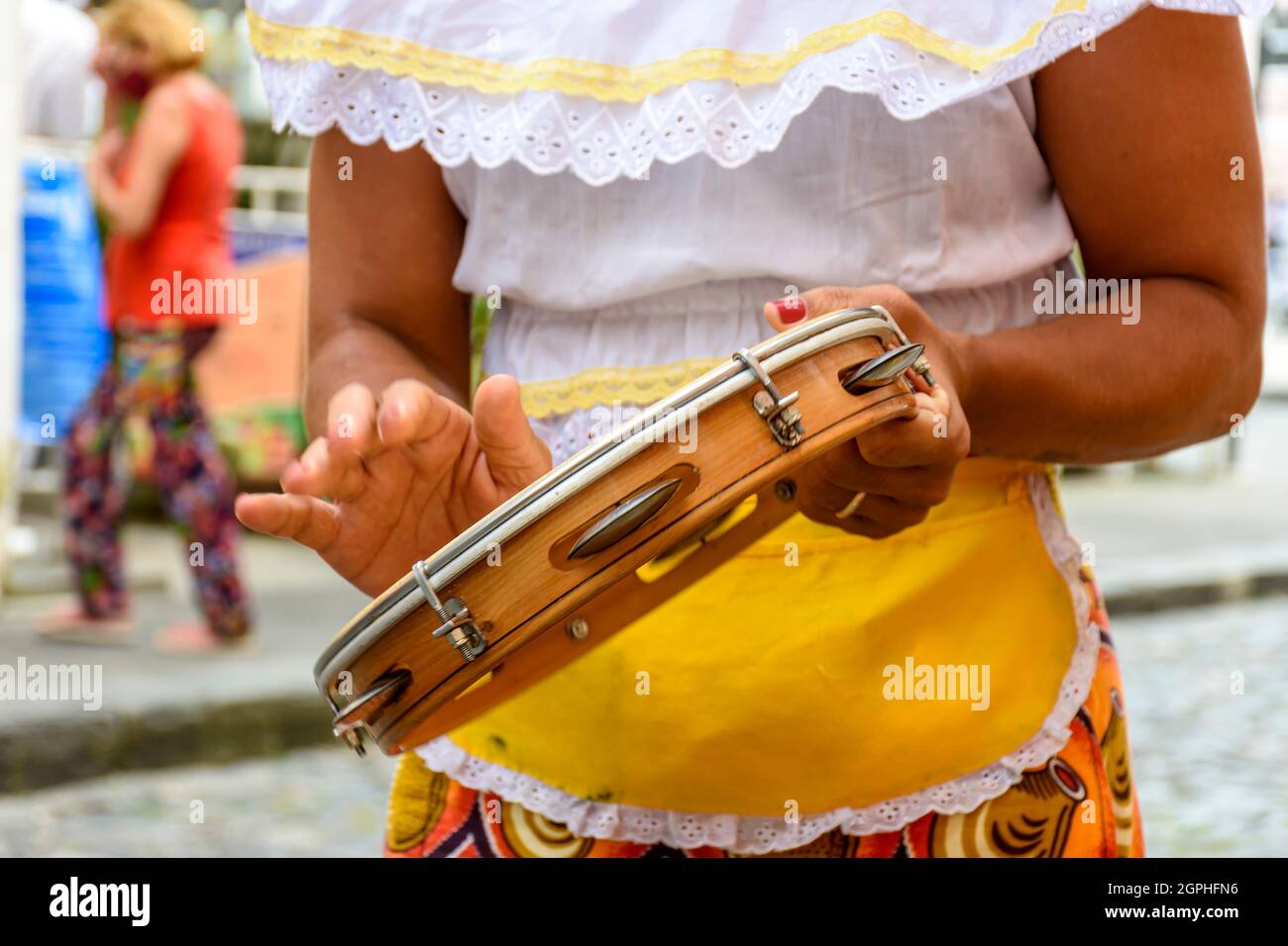 Donna in colorati abiti etnici che giocano a tamburello durante uno spettacolo di samba a Salvador, Bahia Foto Stock