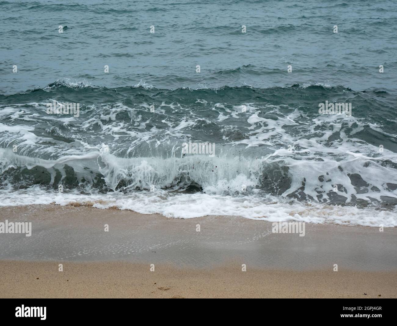 Vista delle onde del mare che si dirigono fortemente verso la riva con un lotto di schiuma nel Parco Tayrona, Colombia Foto Stock