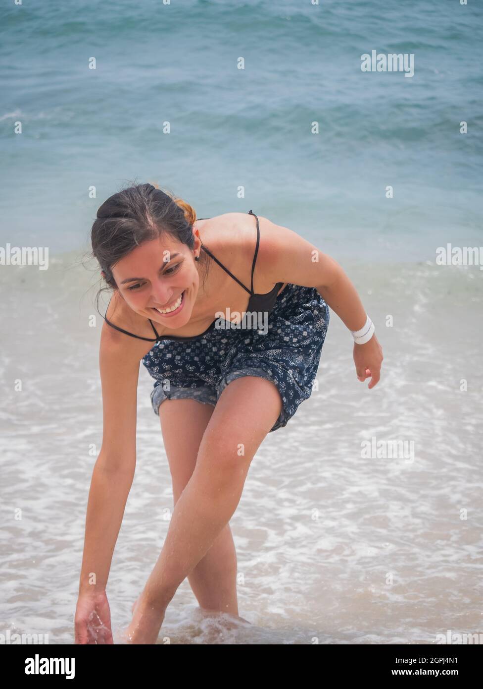 Young Latina Holding un paio di sandali e camminare lungo il Seashore Laughing a Lot Foto Stock