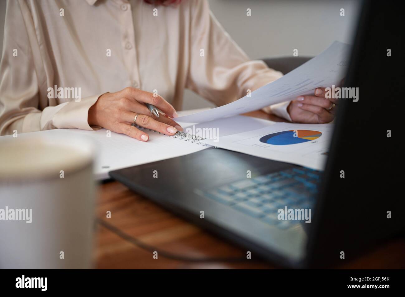 Donna d'affari al suo ufficio lettura attraverso i piani finanziari annuali e rapporti con grafici e grafici. Foto Stock