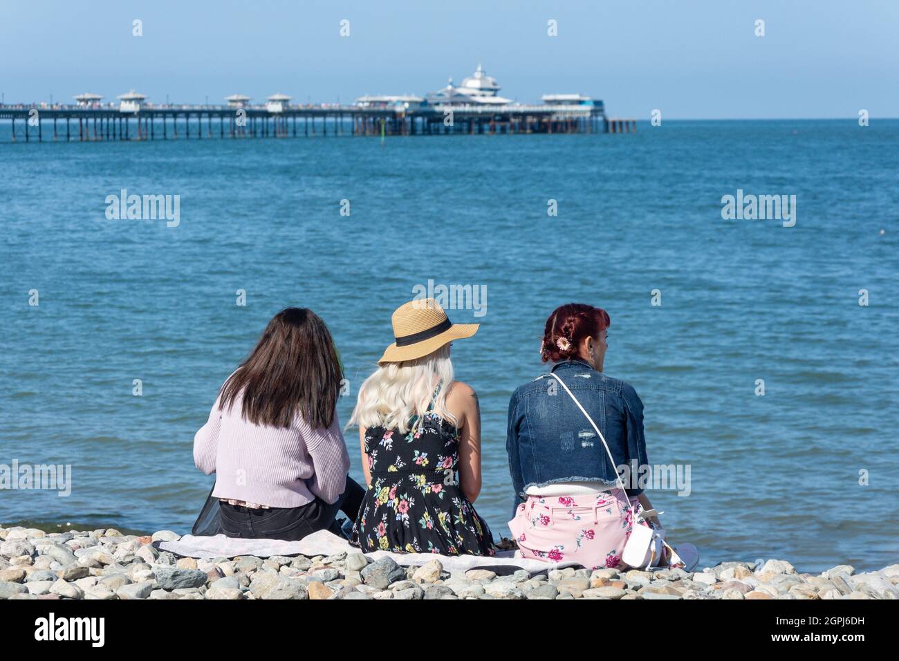 Giovani donne che siedono sulla spiaggia, Llandudno, Conwy County Borough, Galles, Regno Unito Foto Stock